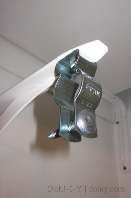 Conduit hanger bolted to a shelf bracket -- shallower alternative to standard closet brackets.