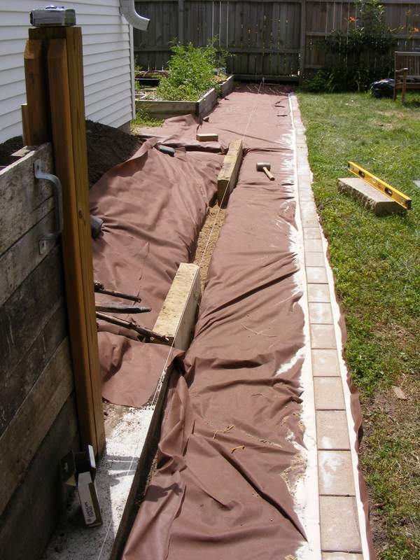The landscape fabric and edging bricks are in place, and the raised bed is taking shape.